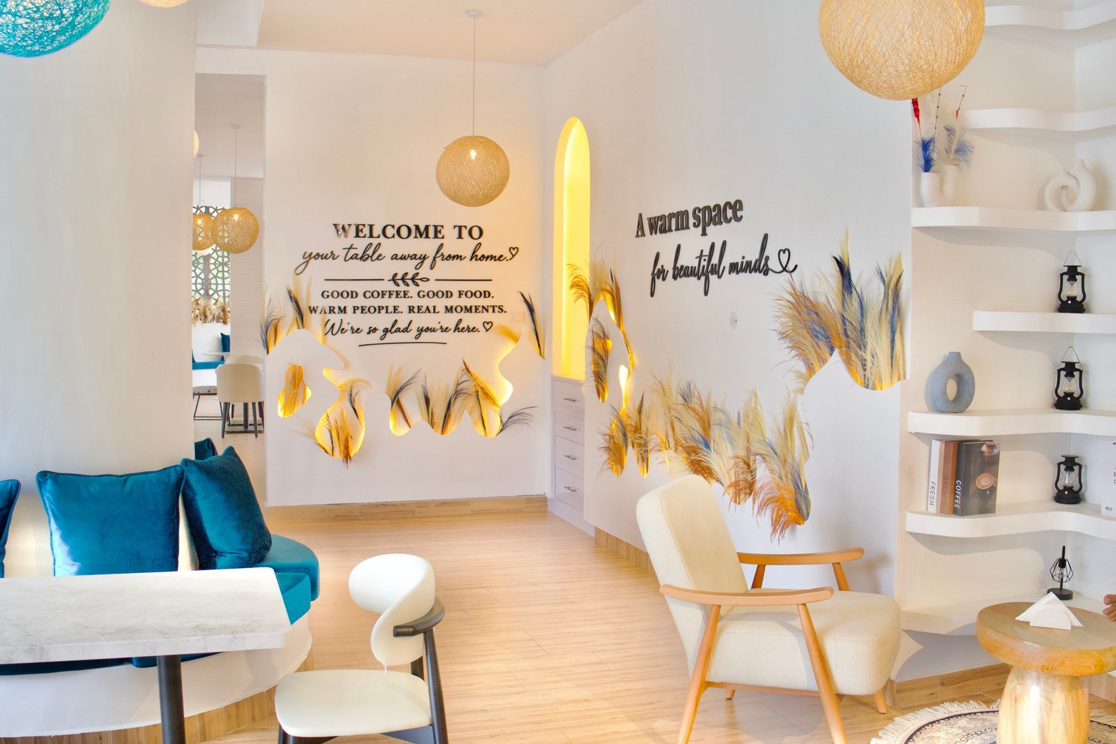 Café Naimora lounge with blue velvet seats, rattan globe lights and the welcome wall