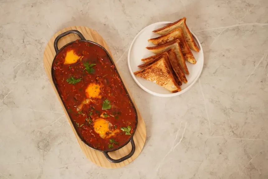 Shakshouka baked eggs in tomato and pepper sauce with sourdough toast